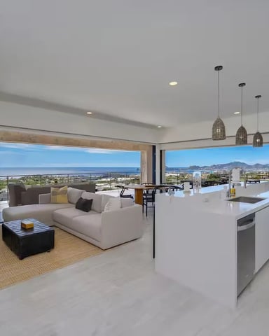 Modern open-plan living room and kitchen with panoramic windows overlooking valley and mountains