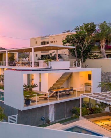 Modern multi-level villa with pool, terraces, and tropical landscaping at sunset