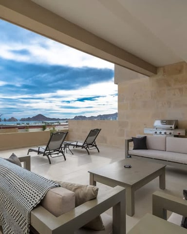 Covered terrace with lounge seating, grill, and panoramic ocean and mountain views