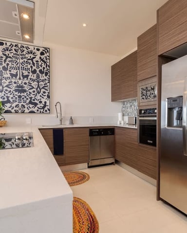 Modern kitchen with white countertops, wood cabinetry, stainless steel appliances, and geometric wall art
