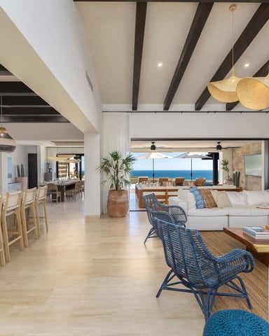 Open-plan coastal home with kitchen, dining area, and living room overlooking ocean view through large glass doors