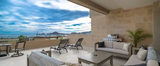 Covered terrace with lounge seating, grill, and panoramic ocean and mountain views