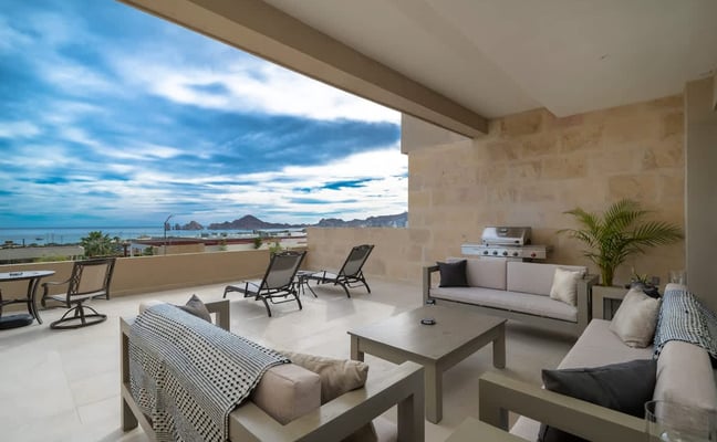 Covered terrace with lounge seating, grill, and panoramic ocean and mountain views